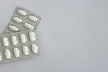 White oblong tablets in silver packages, isolated on a white background. Vitamins and medicines.