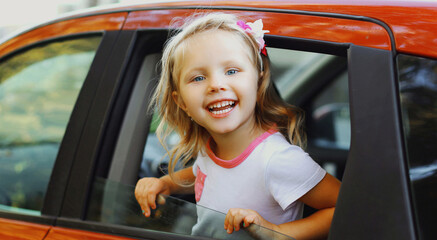 Smiling little child passenger sitting in a red car