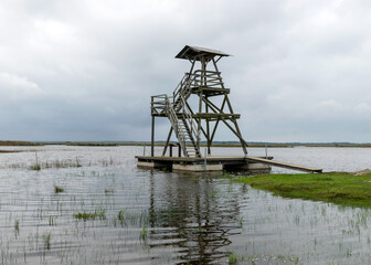 view of bird watching tower, cloudy day, gray clouds, landscape with lake and reeds by the lake