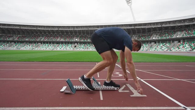 Stadium, professional man sprinter is preparing for the start of a training run in short-distance, track runner, 4k slow motion.