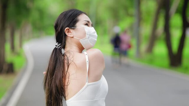 Asian runner jogging in the park during covid-19 pandemic. Working out in the days of the coronavirus.Fit woman jogging at outdoor .Healthy lifestyle concept. she have pois protective mask on face.