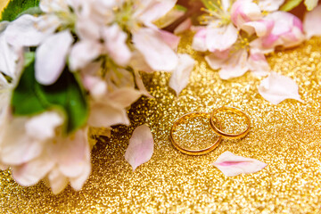 Gold wedding rings and Apple blossoms on a Golden background
