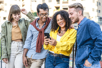 Multiethnic group of friends using smart phone and social media app to connect to the world, millennials people having fun on line, happy multiracial team of college students