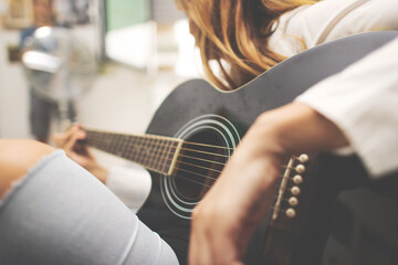 Fototapeta premium Acoustic guitar details in the hand of a left-handed woman