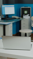 Nobody in consultation space at healthcare clinic used for examination and meeting patients. Empty doctors office with medical equipment and tools, stethoscope and technology devices