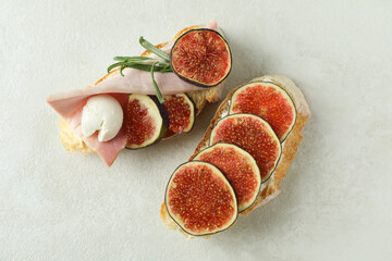 Tasty bruschetta with fig on white textured background