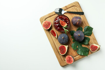 Fototapeta na wymiar Board with fig jam, ingredients and spoon on white background