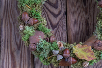 Closeup handmade autumn wreath from natural materials on dark wooden background. Autumn home decor concept.