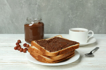 Concept of tasty breakfast with chocolate paste on white wooden table