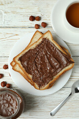 Concept of tasty breakfast with chocolate paste on white wooden table