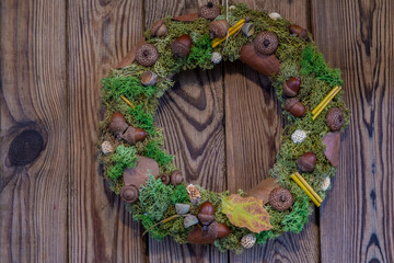 Handmade autumn wreath from natural materials on dark wooden background. Autumn home decor concept.