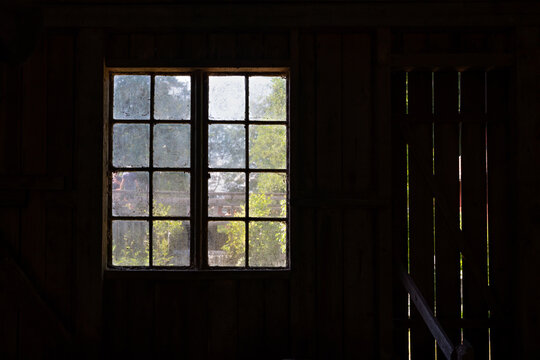 Looking through an old dirty farm house window from the inside with summer view.