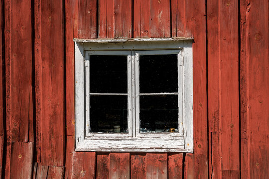 Closeup of a worn window on a old traditional Swedish red wooden building.