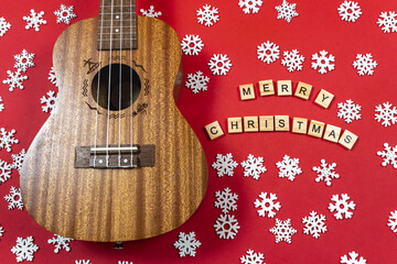Ukulele with copy space Christmas guitar on a red background. An invitation to New Year's musical...