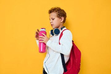 teenager pink water bottle joy fun headphones posing yellow background