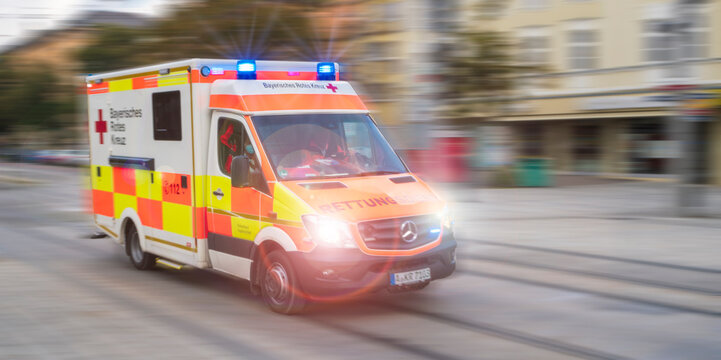 Ein Rettungsfahrzeug vom Roten Kreuz fährt mit Blaulicht und hoher Geschwindigkeit durch Augsburg