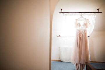 The perfect wedding dress with a full skirt on a hanger in the room of the bride