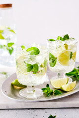 Cold refreshing summer lemonade mojito in a glass on a grey concrete or stone background. Copy space.