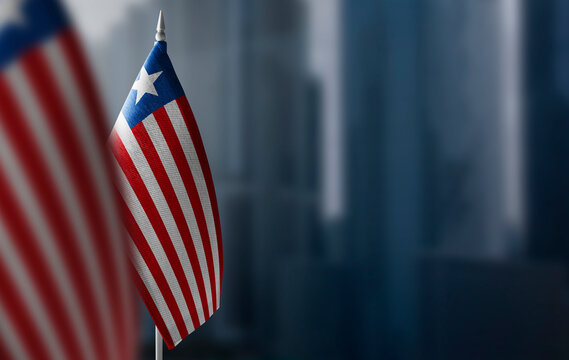 Small flags of Liberia on a blurry background of the city