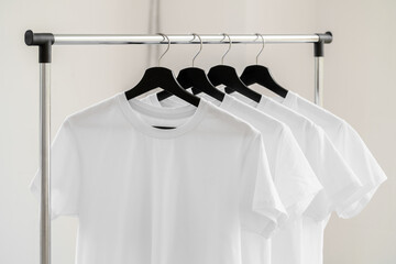 Row of white t-shirts on hangers on rack