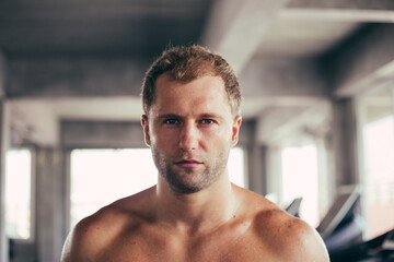 Naklejka na ściany i meble Portrait face of topless male intense looking at camera. Handsome athletic man sweating after workout in the fitness.