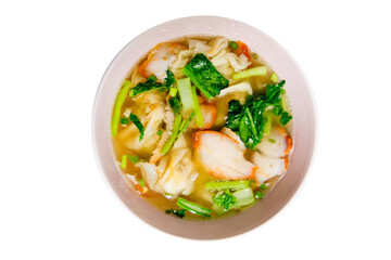 View from the top of a bowl of Chinese pork dumpling soup with vegetables on white background.