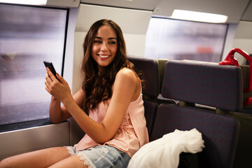 Young woman travelling by train. Beautiful girl using the phone while travel.