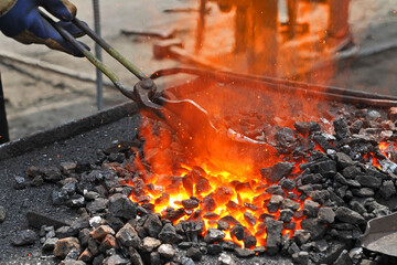 Blacksmith heats the metal workpiece on the blacksmith's furnace