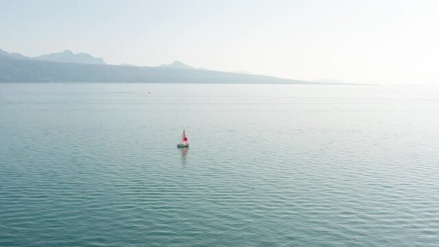 Flying towards a small sail boat on a vast, blue lake