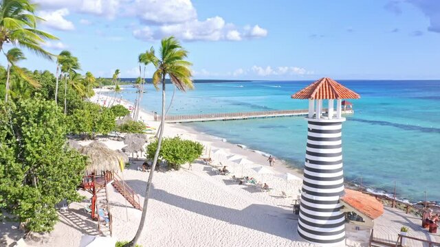 Lighthouse On White Sand Beach With People Relaxing On A Sunny Day. Dominicus Beach In Bayahibe, Dominican Republic. drone shot