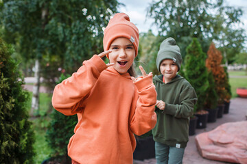 Kids in trendy hats and hoodies having fun in the park, fall vibes, autumn beauty style, child...