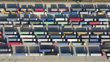 Fototapeta premium Top view of many trucks with trailers waiting to be unloaded at the port terminal.