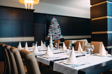 Table setting in the restaurant. Christmas tree on the background.