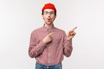 Surprised and curious funny bearded man in red beanie, glasses folding lips from amazement and...