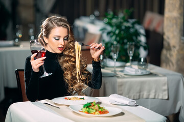 Young beautiful woman eating pasta in a restaurant.