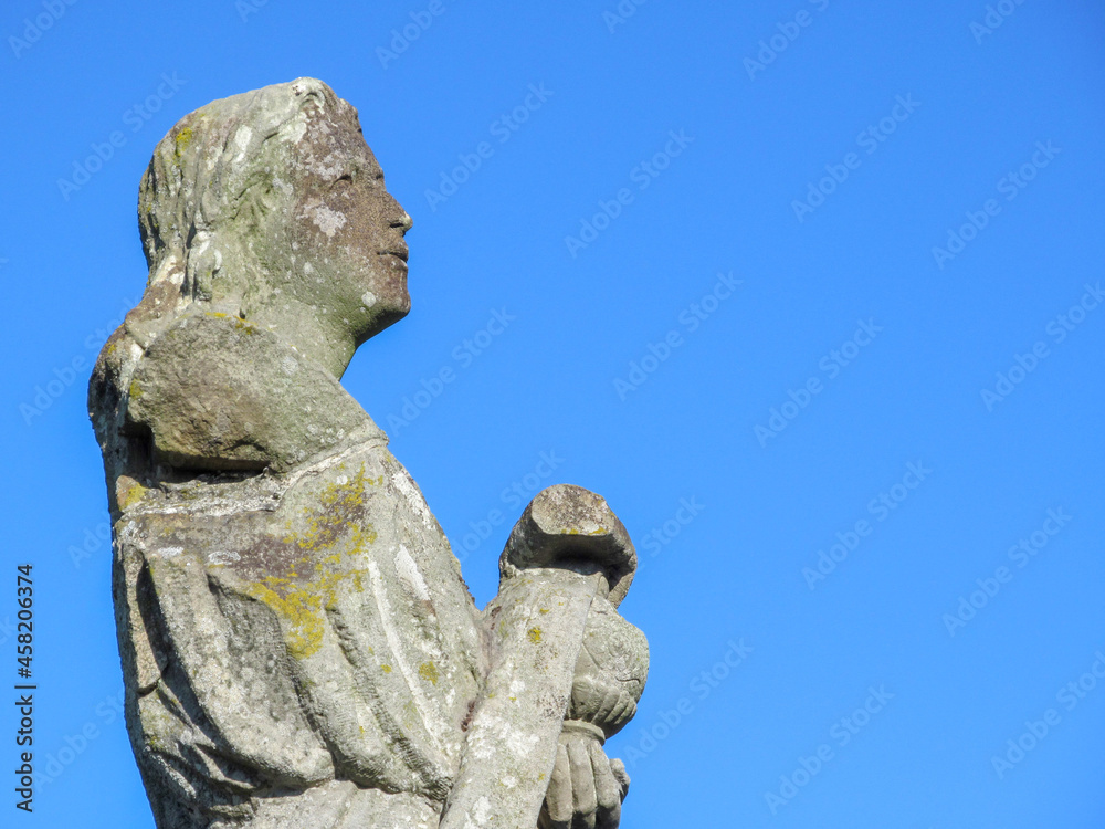 Wall mural Stone monument of a woman with a bowl in her hands on a background of blue sky - Wall murals
