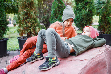 Kids in trendy hats and hoodies having fun in the park, fall vibes, autumn beauty style, child...