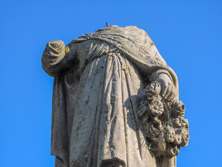 Stone monument of the saint on the grave without a head with a window in his hand - obrazy, fototapety, plakaty