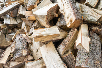 Fuel and heat source for the winter season.Preparing for the firewood heating season. Chopped firewood of different trees,outdoors.