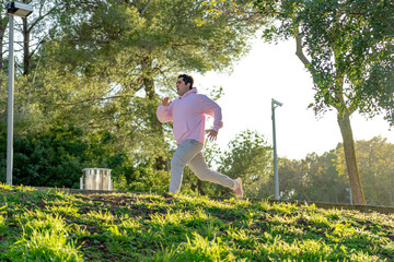 profile of fat man sprinting in the park dressed in sportswear