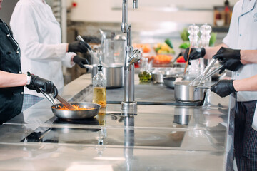 Cooks prepare meals on an electric stove in a professional kitchen in a restaurant or hotel.