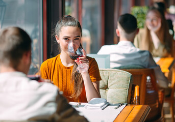 A young couple drinking wine in a restaurant near the window.