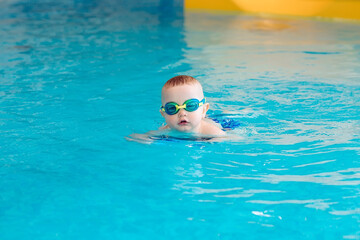 Naklejka premium Baby boy swims independently in the pool.