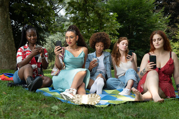 Cinematic shot of young girl friends of different ethnicities using smartphone separately beside...