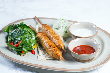 Lula-kebab of chicken with onions and hot red sauce.