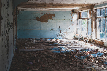 Old non-residential building from inside, peeling paint and fallen plaster with various construction debris on floor close-up