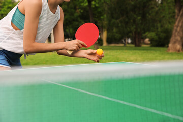 Woman playing ping pong outdoors on summer day, closeup