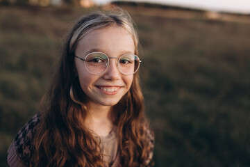 Positive young funny teen girl portrait outdoors. Teenager wearing eye glasses, have fun in park