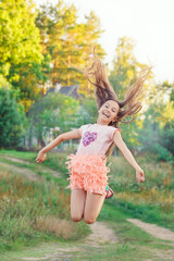 Naklejka na ściany i meble Portrait of Beautiful teenager girl Is jumping and playing at summer sunset.