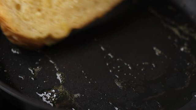 Cooking French toast on a frying pan in butter. Closeup view female chef hand turn over slice of toasted white bread